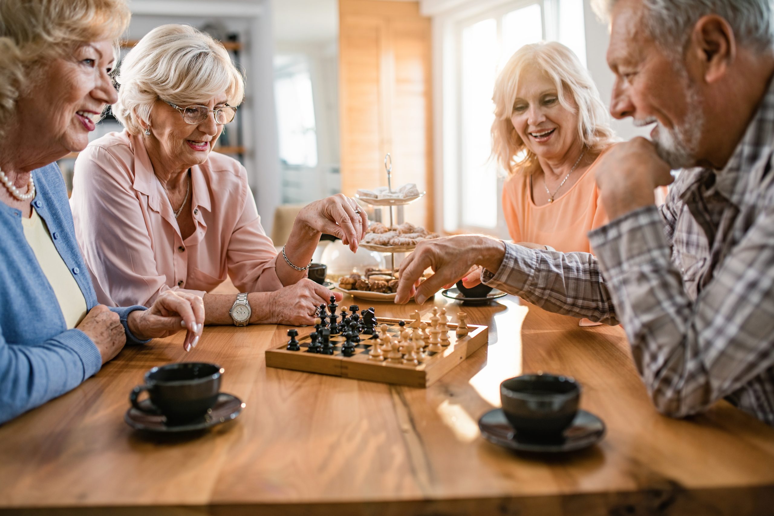 Group of happy seniors playing chess at home.